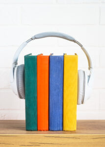 Audio books concept. Wireless Headphones and color books at table.