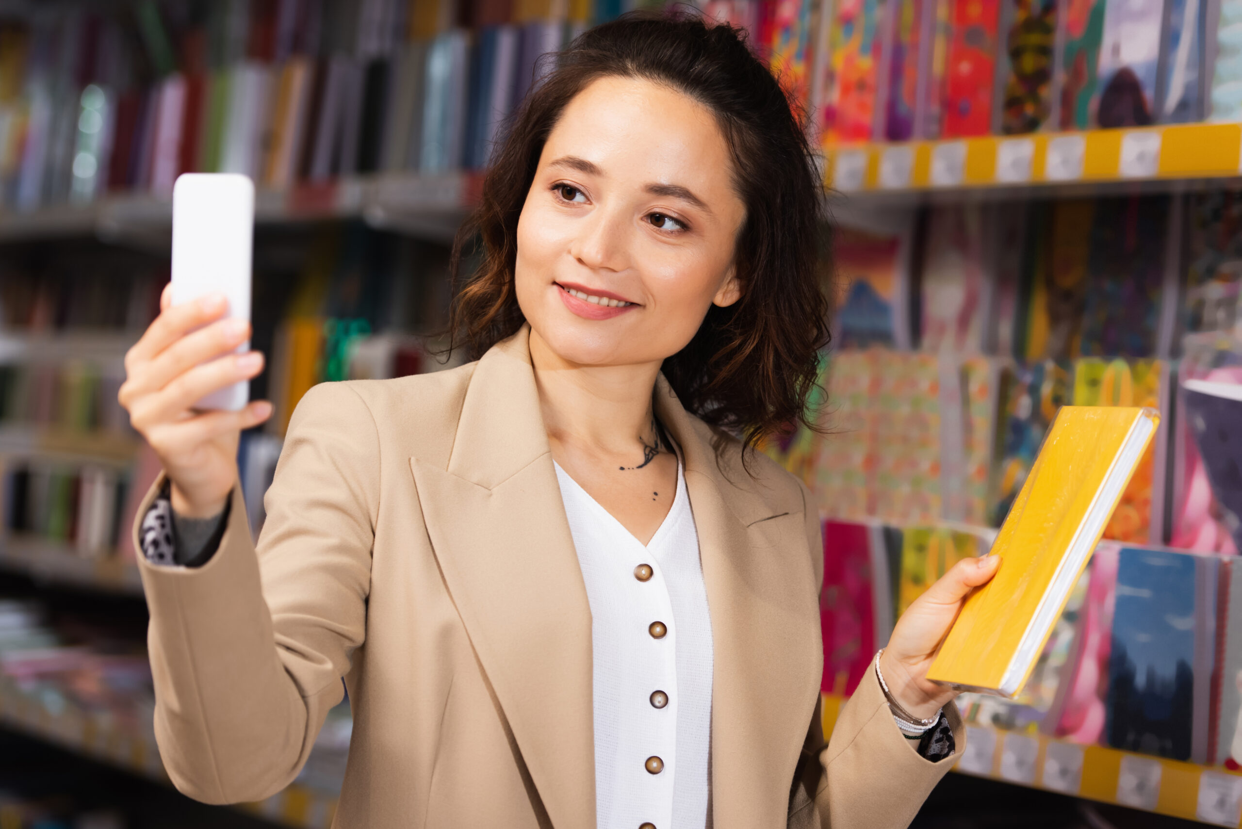 smiling woman taking photo with notebook in stationery shop