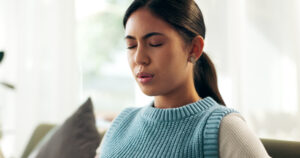 Woman, pain and breathing on couch for anxiety, mental health and panic attack in home. Female pers.